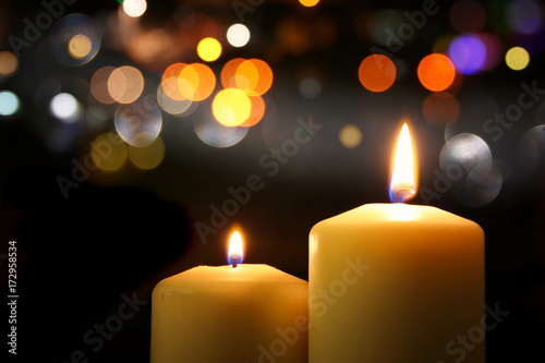 Burning candles over black background with bokeh glitter lights