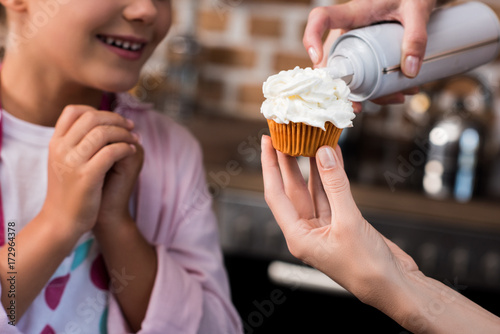 woman putting buttercream on cupcake