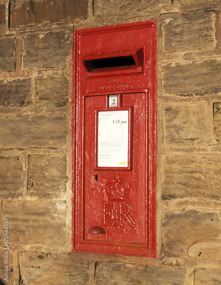 Traditional red Royal Mail post box built into stone wall