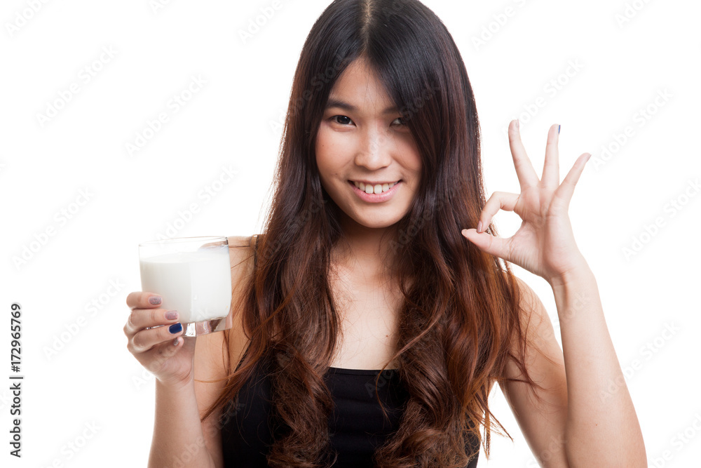 Healthy Asian woman drinking a glass of milk show OK sign.