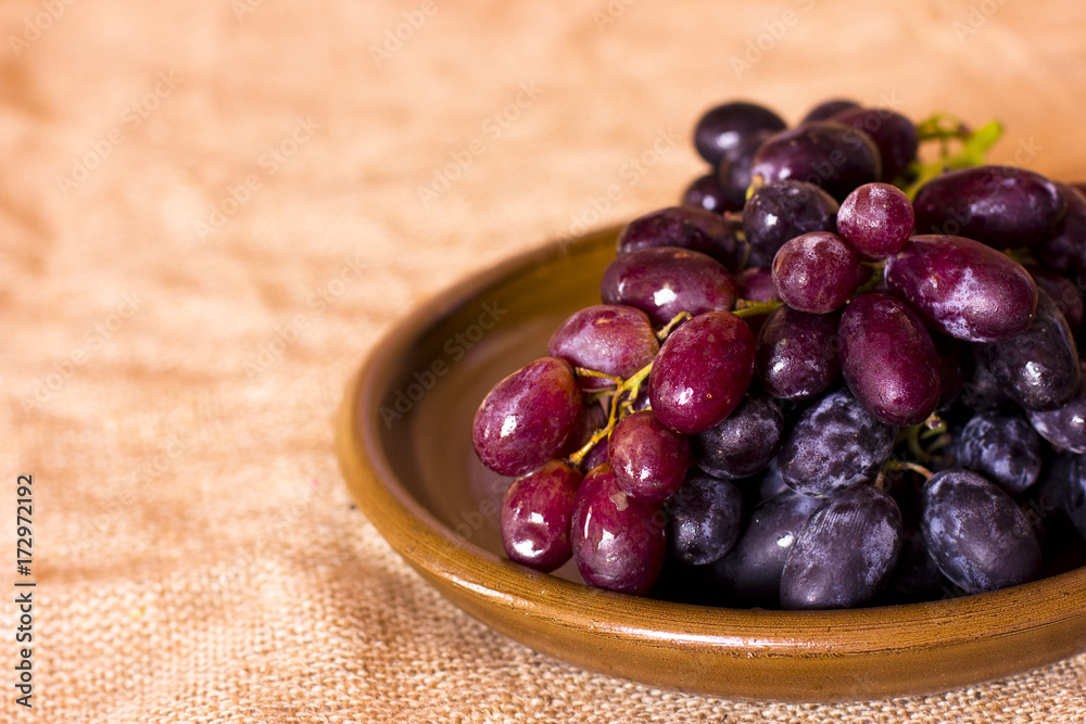 Blue grapes on a clay brown dish Blue grapes on a clay brown dish