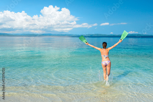 Joyful woman runs to the sea on a tropical beach