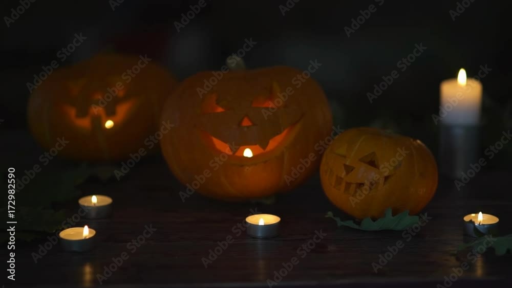 three Halloween Pumpkins head lantern with burning candles on a black background on wooden table with knife and spoon. Celebration of the holiday of Halloween, celebration. three Halloween Pumpkins head lantern with burning candles on a black background on wooden table with knife and spoon. Celebration of the holiday of Halloween, celebration.