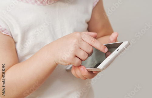 Baby girl hand pointing white smart phone isolated on white background
