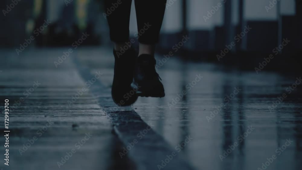Super slow motion close-up shot of female runner's feet running on wet pavement after rain