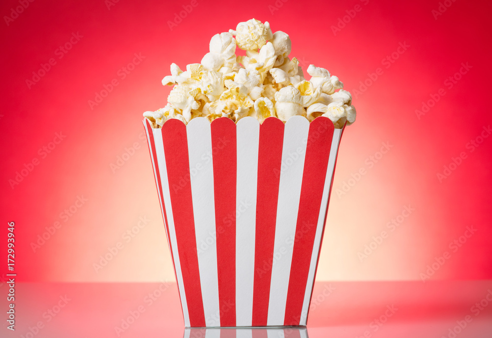 Container with popcorn isolated on a red.