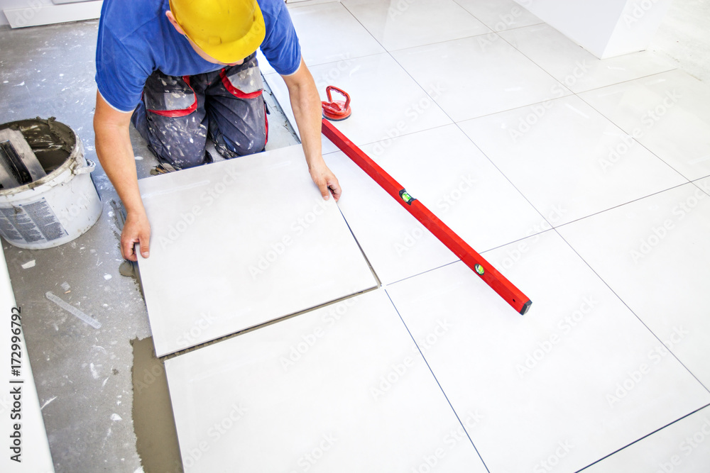 Tile laying tiles at home. Construction worker laid floor tiles. Stock