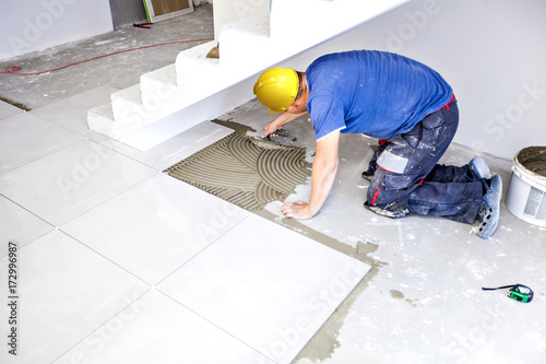 Принти на полотні Tile laying tiles at home. Construction worker laid floor tiles.