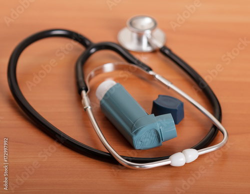 Medical stethoscope and inhaler on the background of table.