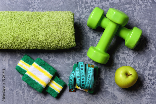 Sports and training idea. Dumbbells in green color and apple