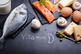 Black slate table with product rich in vitamin D and omega 3. Written word vitamin D by white chalk.