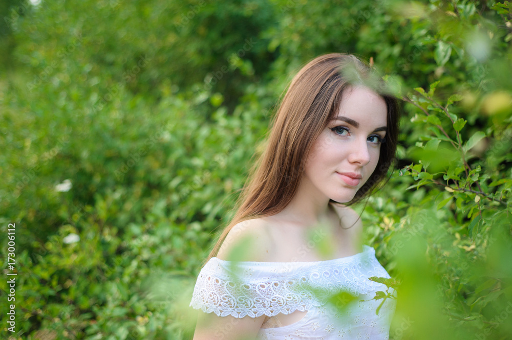 Fototapeta premium portrait of a young beautiful girl in a park in white dress