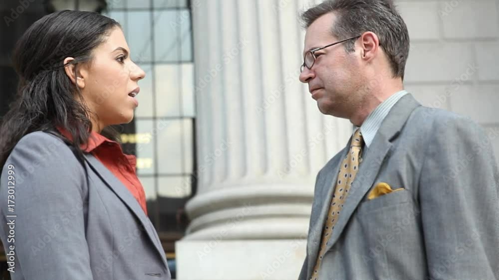 Professionally dressed man and woman having a conversation outdoors on the steps of a building with columns. Could be lawyers, lawyer and client, or business people. Professionally dressed man and woman having a conversation outdoors on the steps of a building with columns. Could be lawyers, lawyer and client, or business people.