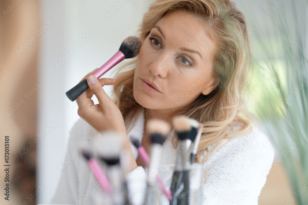 Portrait of 40-year-old woman applying makeup on - mirror view
