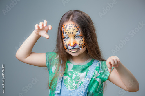 beautiful girl with a tiger painted on his face on a gray background