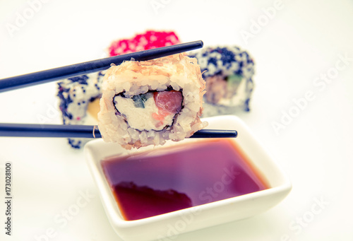 A piece of sushi held by chopsticks 