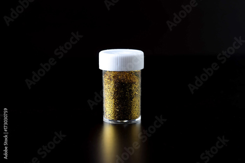 Glitter is in a plastic bowl on a black background.