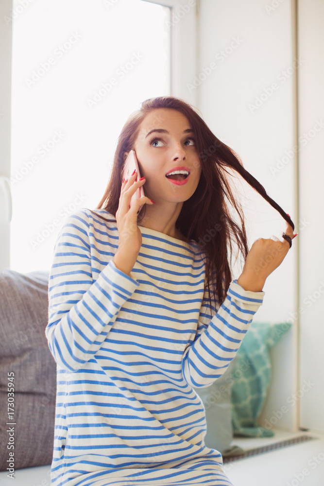 The young attractive woman sitting on the sofa in the room and speaking by the phone The young attractive woman sitting on the sofa in the room and speaking by the phone