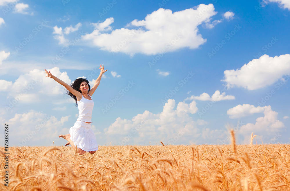 Happy woman jumping in golden wheat, enjoying the life in the field. Nature beauty, blue cloudy sky and field of wheat. Happy outdoor lifestyle. Freedom concept. Woman in summer field Happy woman jumping in golden wheat, enjoying the life in the field. Nature beauty, blue cloudy sky and field of wheat. Happy outdoor lifestyle. Freedom concept. Woman in summer field