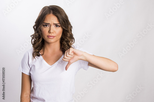 Portrait of a beautiful young girl showing thumbs down isolated on white, body gesture © oreans