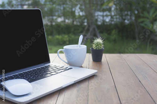 Wooden table with computer and coffee cup. View from above with copy space.