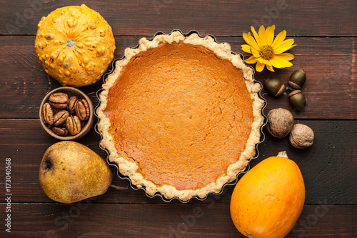 pumpkin homemade pie at wooden background arranged with food ingredients top view