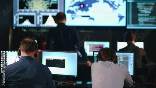 Team of security personnel watching the screens in a system control center. This could be a weather station or airport traffic control room. photo