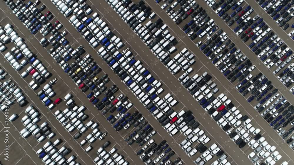 Aerial top down view of vehicle lot showing new produced cars by automakers stored there for further distribution towards car dealers port area where ships bring vehicles in mass production scene 4k Aerial top down view of vehicle lot showing new produced cars by automakers stored there for further distribution towards car dealers port area where ships bring vehicles in mass production scene 4k