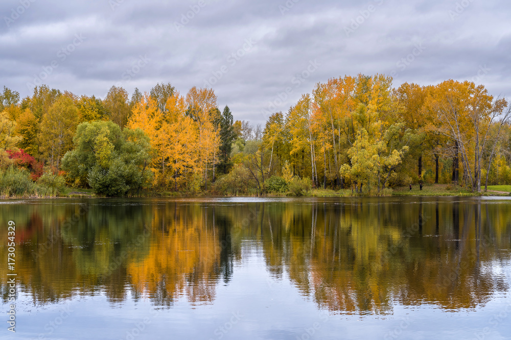 The lake, reflecting the cloudy sky and autumnal foliage trees The lake, reflecting the cloudy sky and autumnal foliage trees
