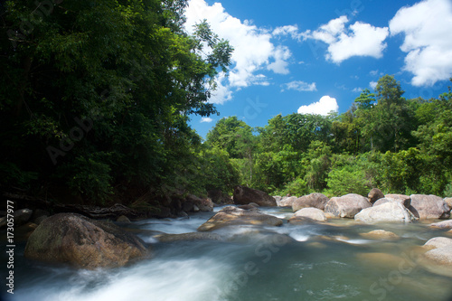 Fototapeta Naklejka Na Ścianę i Meble -  Waterfall in the south of Thailand with blue sky, clouds and lush vegetation in the background