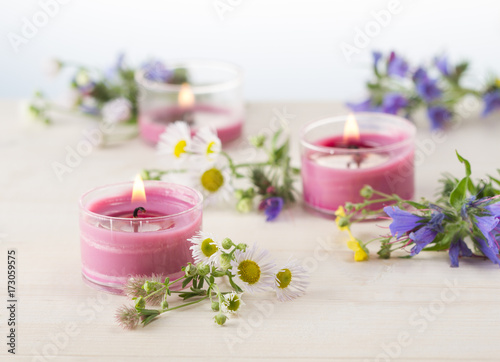 Burning candles and grass blossoms on white wooden table