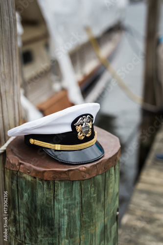 Military naval officer's lid on pier piling - vertical photo