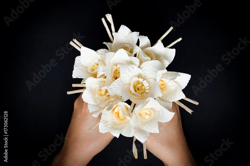 Fototapeta Naklejka Na Ścianę i Meble -  Kind of wood flower bouquet on hand isolated on black background; to be placed on the site of cremation in Thailand. (Dok Mai Jan)