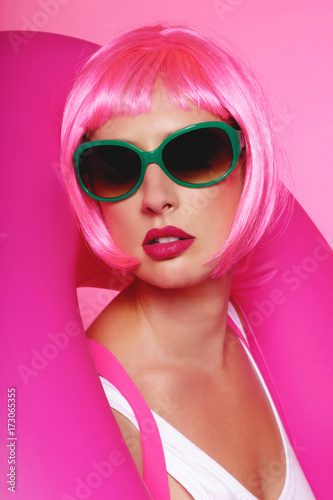 jolie femme perruque cheveux roses souriant avec baudruche et lunettes de soleil 