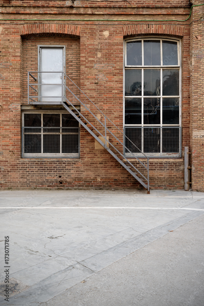 Frontal view of factory facade, old brick wall with window and door Frontal view of factory facade, old brick wall with window and door