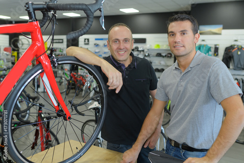portrait of positive men posing in bicycle store