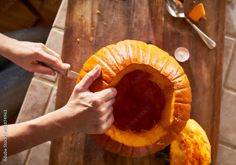 Obraz premium top down view of a woman carving a pumpkin in ktichen