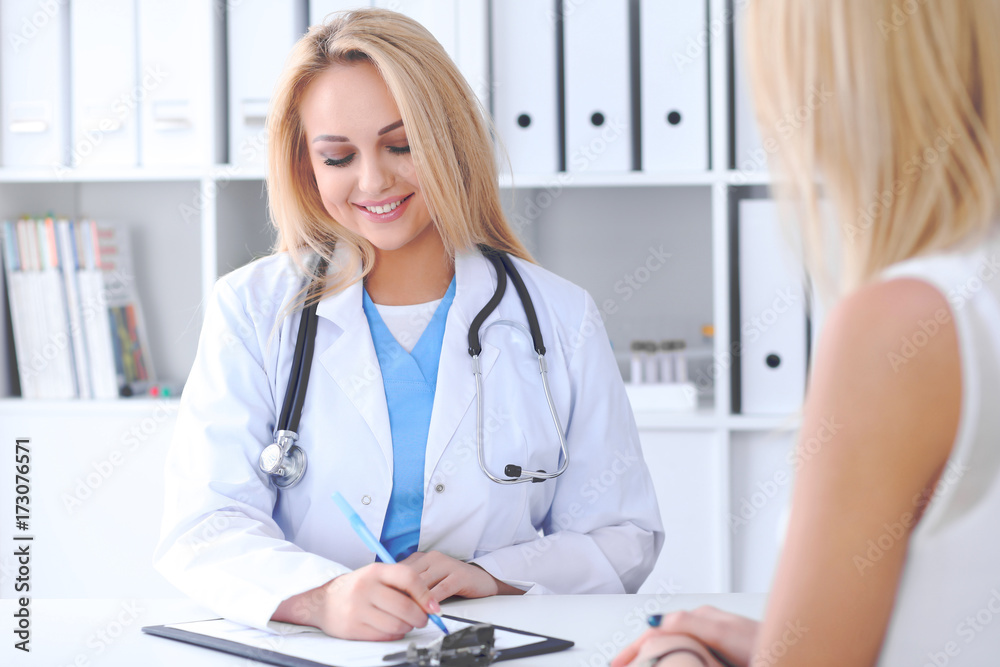 Doctor and patient discussing something while sitting at the table . Medicine and health care concept Doctor and patient discussing something while sitting at the table . Medicine and health care concept