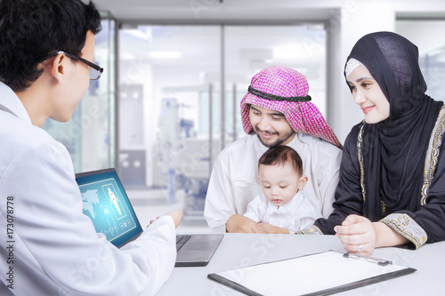 Pediatrician and Arabian family with laptop