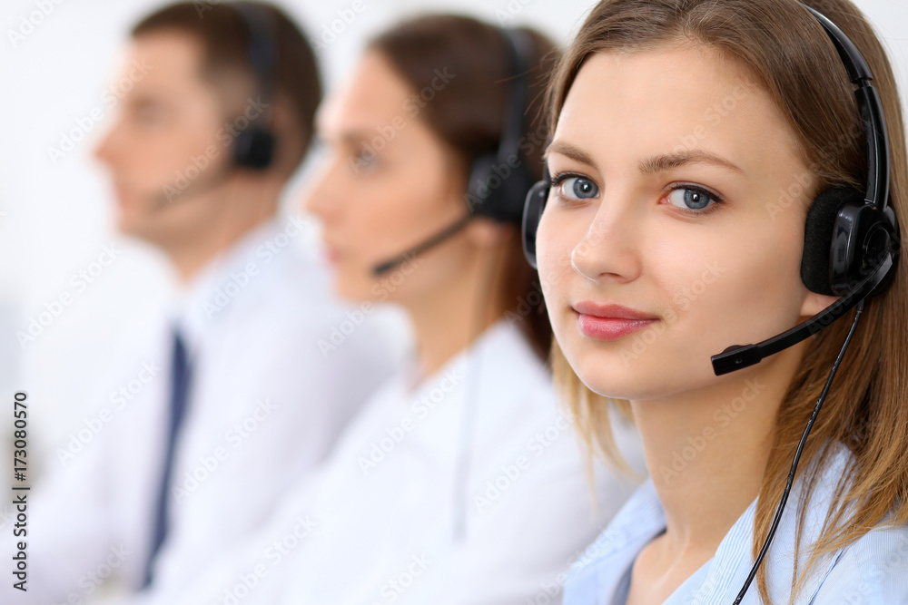 Call center operators. Focus at young beautiful business woman in headset Call center operators. Focus at young beautiful business woman in headset