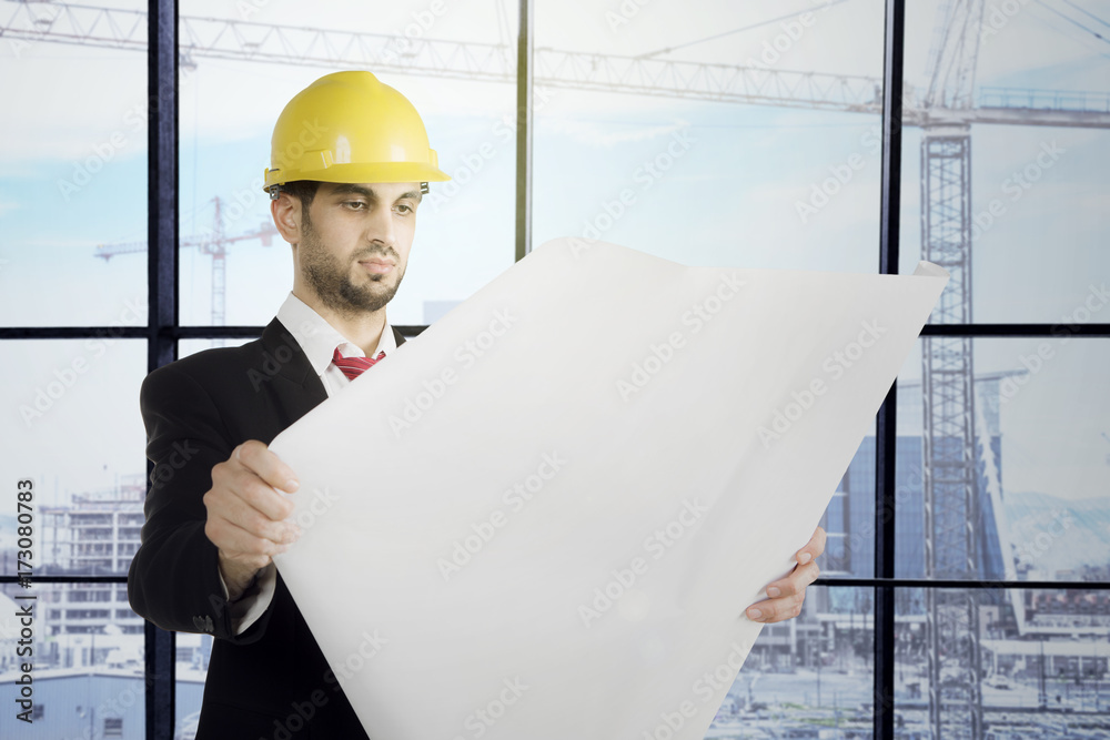 Italian engineer checks blueprint in the office Italian engineer checks blueprint in the office