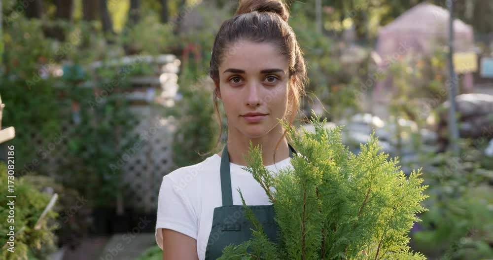 Young lady running a gardening business. Portrait of happy female gardener looking at camera smiling. Medium close up. Slow motion. Young lady running a gardening business. Portrait of happy female gardener looking at camera smiling. Medium close up. Slow motion.
