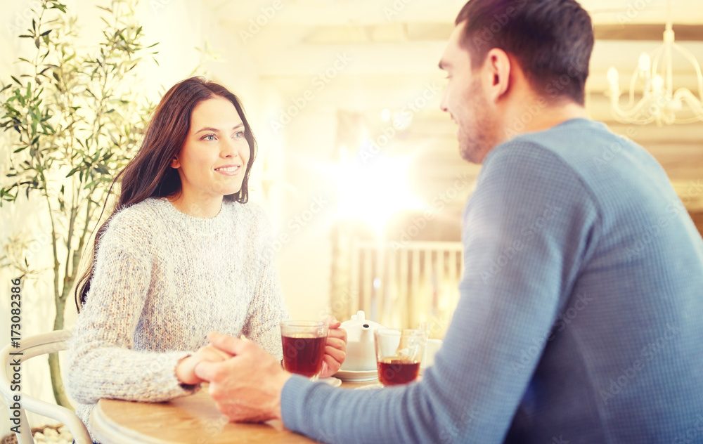 happy couple with tea holding hands at restaurant happy couple with tea holding hands at restaurant