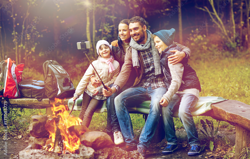 family with smartphone taking selfie near campfire - obrazy, fototapety, plakaty 