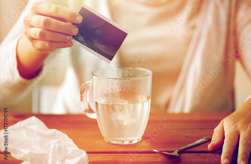 woman pouring medication into cup of water