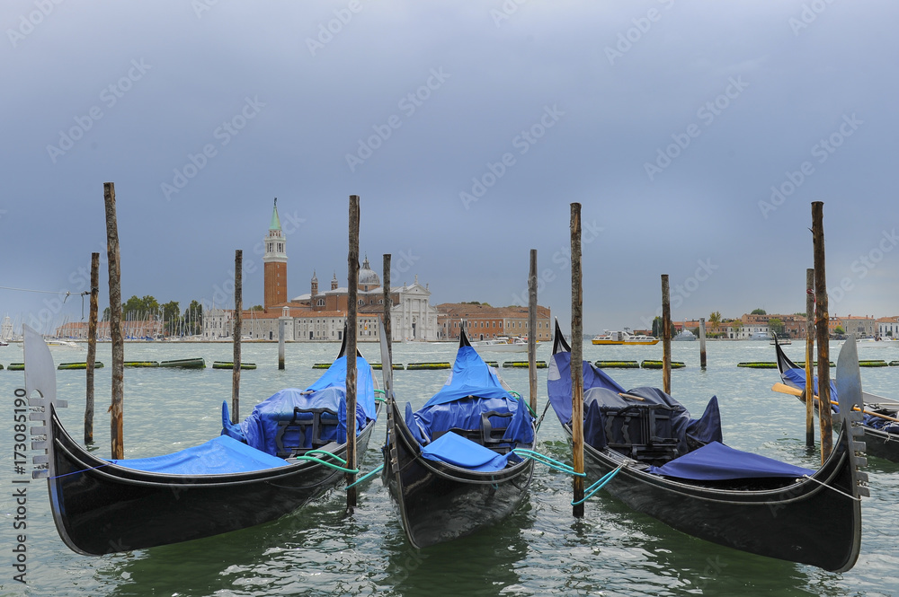 Traditional gondolas in the sea on background of ancient Venice, Italy
