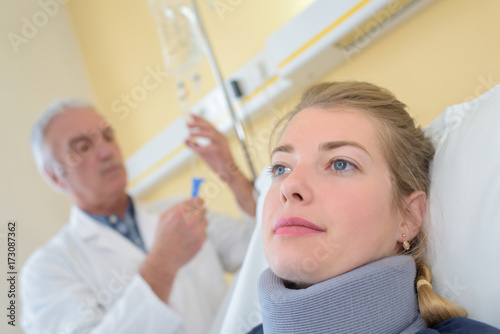 doctor with patient wearing neck brace in hospital room