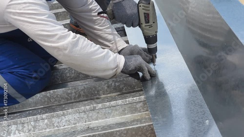 The roofer drills metal a drill