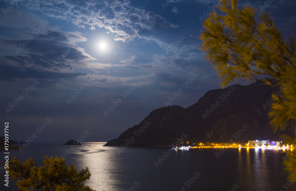 Evening view of the town of Icmeler. The bay is surrounded by mountains. Night life. Beach illuminated by evening lights