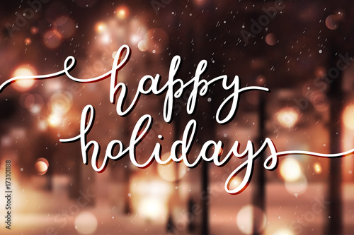 happy holidays lettering, vector handwritten text on blurred background of winter street